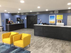 uma sala de espera com duas cadeiras amarelas e um balcão em Days Inn & Suites by Wyndham Cincinnati North em Springdale