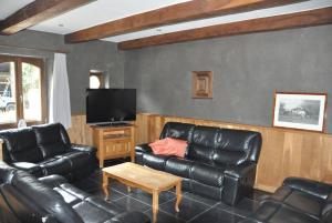 sala de estar con muebles de cuero y TV de pantalla plana en Gîte Ferme d'Ortie en Sainte-Ode