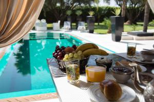een tafel met eten en drinken naast een zwembad bij Villa Mano in Marrakesh