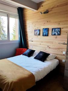 ein Schlafzimmer mit einem großen Bett und einer Holzwand in der Unterkunft Résidence Le Fontenay in Plateau dʼAssy