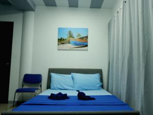 a bedroom with a bed with blue sheets and a chair at Mactan-Cebu Airport Budget Hotel in Mactan