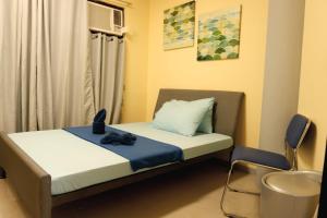 a small bedroom with a bed and a chair at Transit Point Hostel Mactan Cebu in Mactan