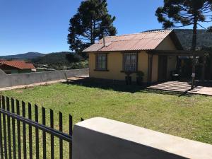 a small yellow house with a fence in front of it at Chalés Energias da Serra in Bom Jardim da Serra