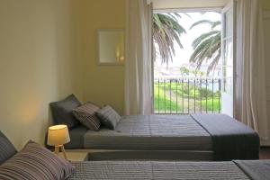 Un dormitorio con dos camas y una gran ventana. en Downtown Ponta Delgada, en Ponta Delgada