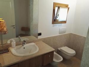 ein Badezimmer mit einem Waschbecken, einem WC und einem Spiegel in der Unterkunft Il giuggiolo in Conegliano