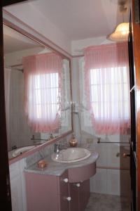 a bathroom with a sink and a mirror and pink curtains at Casa Gusber I in El Paso