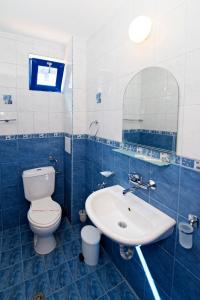 a blue and white bathroom with a toilet and a sink at Hotel Penelope in Primorsko