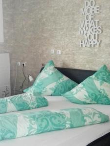 Una cama con almohadas verdes y blancas. en Heidi's ART, en Arnsberg