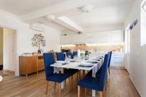 a dining room with a long table and blue chairs at Villa Branca do Castelo in Sesimbra