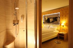 1 dormitorio con 1 cama y ducha en una habitación en Hotel Pineta, en Baselga di Pinè