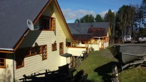 una casa con un barco delante de ella en Chile Lodge - Lago Huillinco, en Notuél