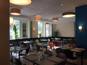 a dining room with tables and chairs and windows at Hotel Continental in Nuremberg