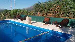 a swimming pool with chairs and a table next to a pool at Cabañas Esferas de Cristal in Capilla del Monte