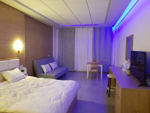 une chambre d'hôtel avec un lit et une lumière violette dans l'établissement סנו נופש בגולן, à Majdal Shams