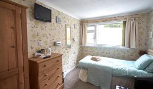 a bedroom with a bed and a dresser and a window at Greenacre in Oban