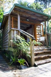 Cabaña de madera con escaleras y porche en Hush Boutique Accommodation, en Coromandel