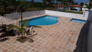 - une piscine sur une terrasse carrelée avec une table et des chaises dans l'établissement Apto Confortável em Frente às Dunas Do Atalaia, à Salinópolis