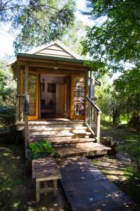 Cabaña pequeña con porche de madera y banco en Hush Boutique Accommodation, en Coromandel