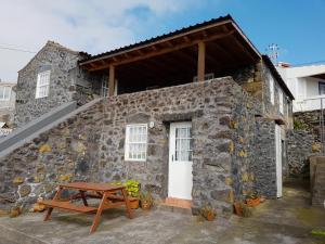 - un bâtiment en pierre avec une table de pique-nique devant dans l'établissement Adega da Figueira, à Calheta de Nesquim