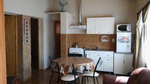 a kitchen with a table and chairs and a kitchen with white cabinets at Cabañas Casa de colores in Maimará