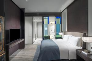 una camera d'albergo con letto e TV di Sofitel Foshan Shunde a Shunde