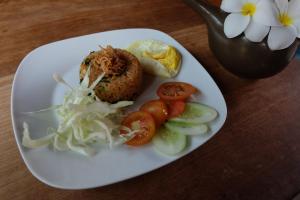 a plate of food with tomatoes and vegetables on a table at Semarandana Bedrooms and Pool in Sanur