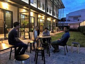 a group of people sitting at tables in front of a building at THE TREE Sleep and Space in Trang