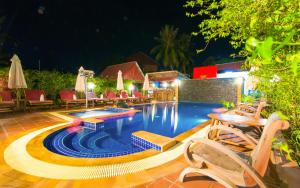 una piscina por la noche con sillas y sombrillas en Blossoming Romduol Boutique, en Siem Reap