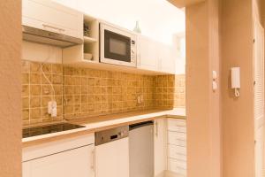 a kitchen with white cabinets and a microwave at Chic and Very Central in Budapest