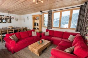 a living room with a red couch and a table at Chalet De La Vanoise in Montchavin