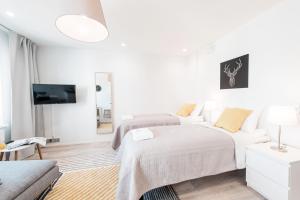 a white bedroom with two beds and a tv at Forenom Serviced Apartments Helsinki Lauttasaari in Helsinki
