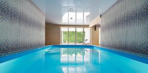 a swimming pool in a house with blue water at Lebediny Guest House in Brest