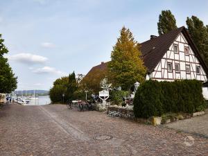 a house on the shore of a lake with a cobblestone street at Café Perlmuschel in Iznang