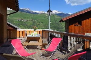 two chairs and a table on a deck with mountains at La maison de Marie in Valmorel