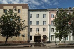 a large white building on a street with trees at Hotel Sofia in Velikiy Novgorod