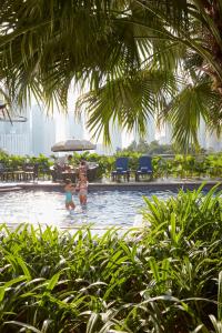 zwei Kinder spielen im Pool eines Resorts in der Unterkunft Mandarin Oriental, Kuala Lumpur in Kuala Lumpur