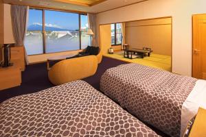 um quarto de hotel com duas camas e uma secretária em KKR Numazu Hamayu em Numazu