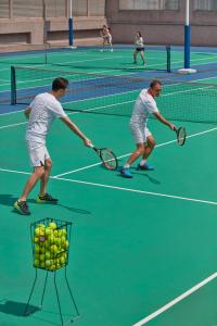 two men playing tennis on a tennis court at Mandarin Oriental, Kuala Lumpur in Kuala Lumpur