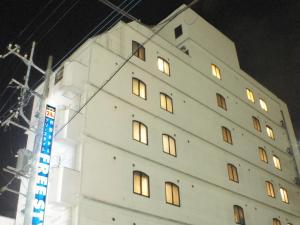 a white building with lit windows at night at Hotel Free Style in Kofu