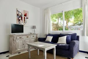 a living room with a blue couch and a tv at Hacienda Encanto del Rio in Santa Eularia des Riu