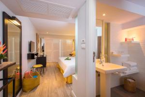 ein Schlafzimmer mit einem Bett und ein Badezimmer mit einem Waschbecken in der Unterkunft Burasari Phuket Resort & Spa in Patong Beach
