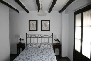 1 dormitorio con 1 cama y 2 cuadros en la pared en Casa Rural Villalta, en Priego de Córdoba