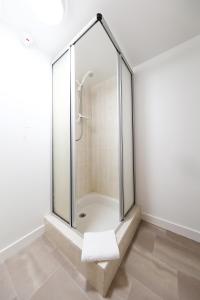 uma cabina de duche em vidro numa casa de banho branca com uma toalha em The Station Hotel em Carnoustie