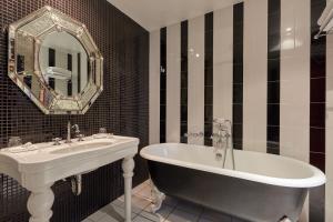 a black and white bathroom with a tub and a sink at Hôtel du Petit Moulin, Haute Couture hotel by Lacroix in Paris +69 photos