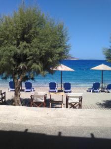 a beach with chairs and tables and a tree at Nektaria on the Beach in Fournoi