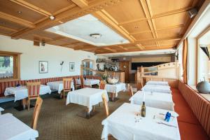 une salle à manger avec des tables et des chaises blanches dans l'établissement Hotel Wildschütz, à San Leonardo in Passiria