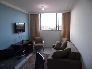 ein Wohnzimmer mit einem Sofa und einem TV in der Unterkunft Apartamento para temporada in Campina Grande