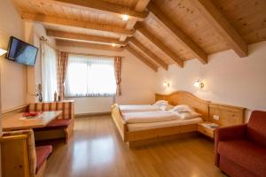 a bedroom with a bed and a couch and a tv at Garnì Lasteis B&B - apartments in La Villa