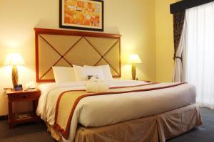 アブダビにあるアル ディアル ミナ ホテルのランプ2つが備わる客室の大型ベッド1台分です。