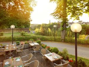 a patio with tables and chairs in a garden at Hotel Parc Belle-Vue in Luxembourg